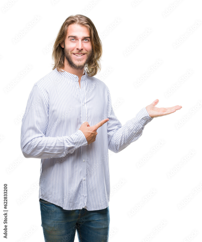 Young handsome man with long hair over isolated background amazed and smiling to the camera while presenting with hand and pointing with finger. Young handsome man with long hair over isolated background amazed and smiling to the camera while presenting with hand and pointing with finger.