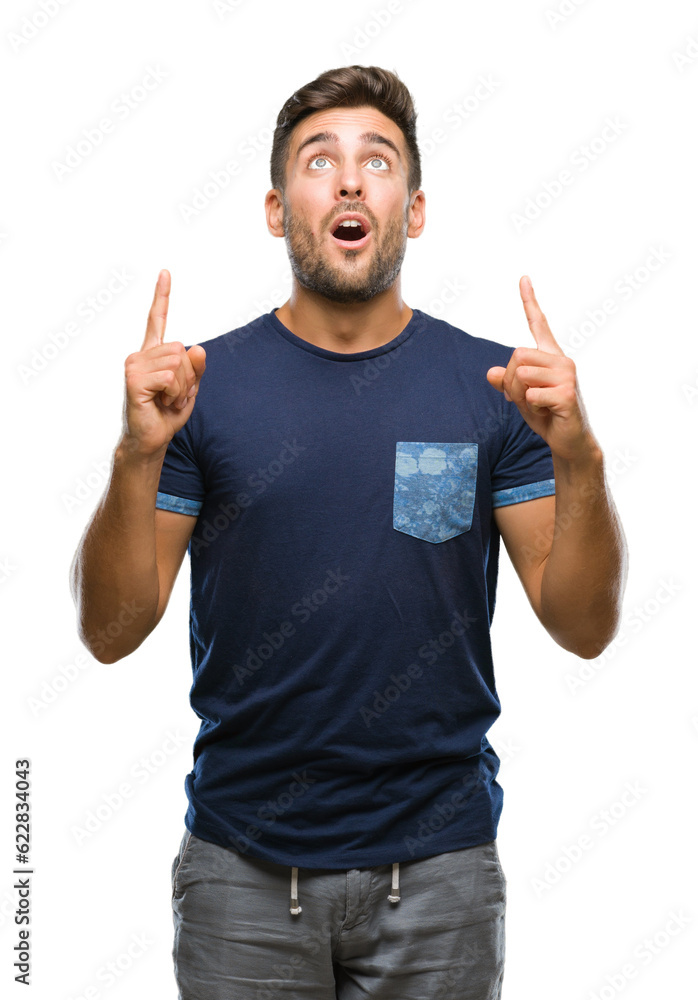 Young handsome man over isolated background amazed and surprised looking up and pointing with fingers and raised arms. Young handsome man over isolated background amazed and surprised looking up and pointing with fingers and raised arms.