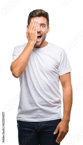 Young handsome man over isolated background covering one eye with hand with confident smile on face and surprise emotion.