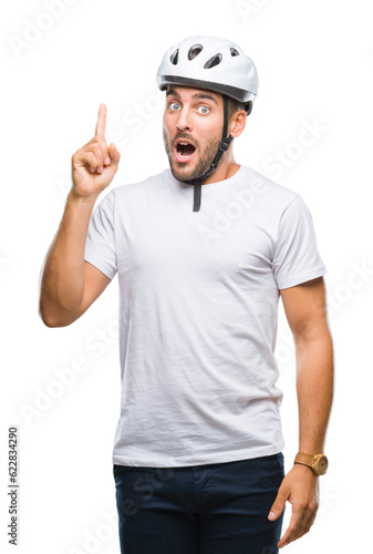 Young handsome man wearing cyclist safety helmet over isolated background pointing finger up with successful idea. Exited and happy. Number one.
