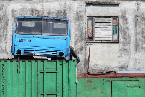 Photography A cabin of a truck sitting on top of a container and a facade of a house in the