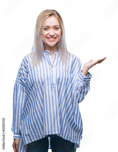 Young blonde woman over isolated background smiling cheerful presenting and pointing with palm of hand looking at the camera.