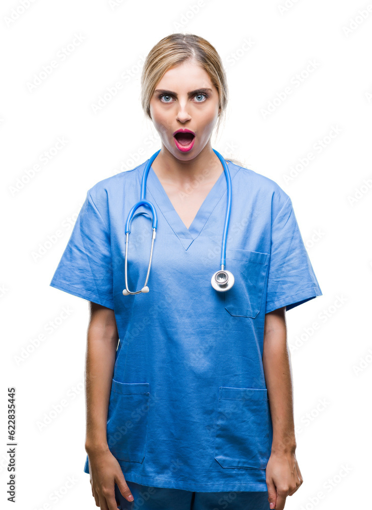 Young beautiful blonde doctor surgeon nurse woman over isolated background afraid and shocked with surprise expression, fear and excited face. Young beautiful blonde doctor surgeon nurse woman over isolated background afraid and shocked with surprise expression, fear and excited face.