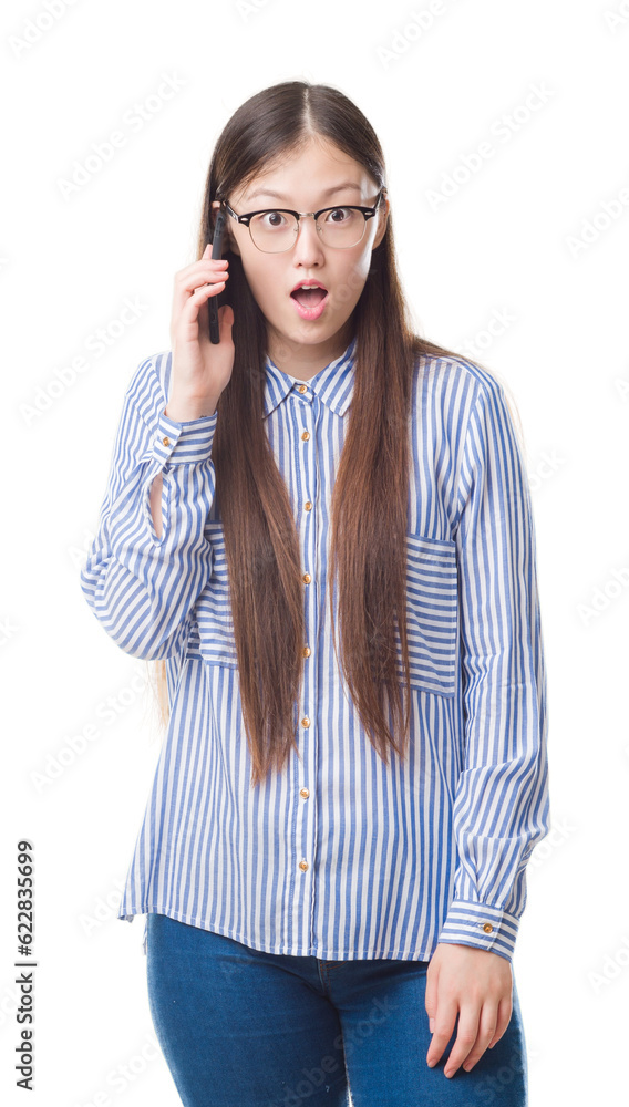 Young Chinese woman over isolated background speaking on the phone scared in shock with a surprise face, afraid and excited with fear expression Young Chinese woman over isolated background speaking on the phone scared in shock with a surprise face, afraid and excited with fear expression