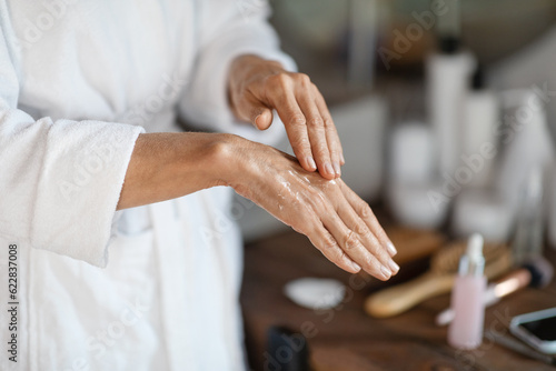 Dry Skin Treatments. Mature woman applying anti-aging serum on hands at home