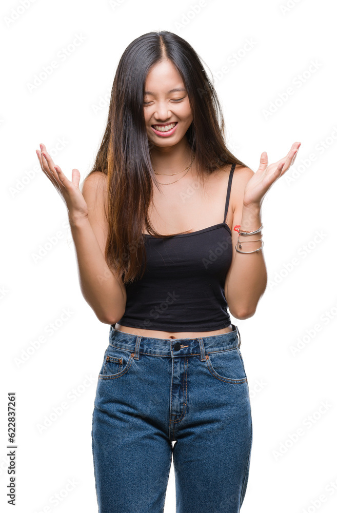 Young asian woman over isolated background celebrating mad and crazy for success with arms raised and closed eyes screaming excited. Winner concept Young asian woman over isolated background celebrating mad and crazy for success with arms raised and closed eyes screaming excited. Winner concept