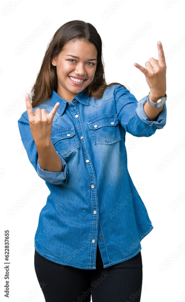 Young beautiful brunette woman wearing blue denim shirt over isolated background shouting with crazy expression doing rock symbol with hands up. Music star. Heavy concept. Young beautiful brunette woman wearing blue denim shirt over isolated background shouting with crazy expression doing rock symbol with hands up. Music star. Heavy concept.
