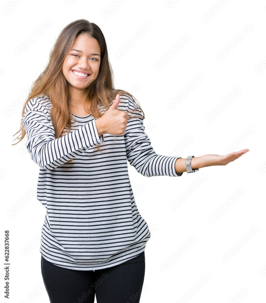 Young beautiful brunette woman wearing stripes sweater over isolated background Showing palm hand and doing ok gesture with thumbs up, smiling happy and cheerful Young beautiful brunette woman wearing stripes sweater over isolated background Showing palm hand and doing ok gesture with thumbs up, smiling happy and cheerful
