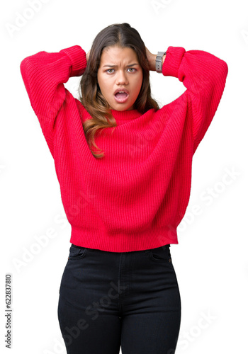 Young beautiful brunette woman wearing red winter sweater over isolated background Crazy and scared with hands on head, afraid and surprised of shock with open mouth © Krakenimages.com