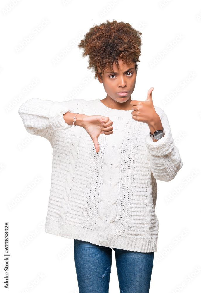 Beautiful young african american woman wearing winter sweater over isolated background Doing thumbs up and down, disagreement and agreement expression. Crazy conflict Beautiful young african american woman wearing winter sweater over isolated background Doing thumbs up and down, disagreement and agreement expression. Crazy conflict