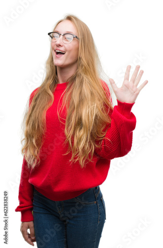 Blonde teenager woman wearing red sweater showing and pointing up with fingers number five while smiling confident and happy.