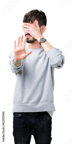 Young handsome man wearing sweatshirt over isolated background covering eyes with hands and doing stop gesture with sad and fear expression. Embarrassed and negative concept. © Krakenimages.com