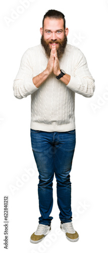 Young hipster man wearing winter sweater praying with hands together asking for forgiveness smiling confident.