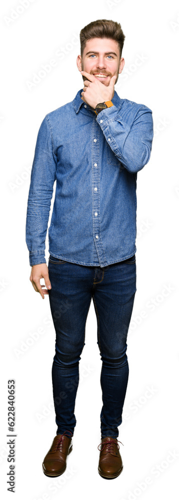 Young handsome blond man wearing casual denim shirt looking confident at the camera with smile with crossed arms and hand raised on chin. Thinking positive. Young handsome blond man wearing casual denim shirt looking confident at the camera with smile with crossed arms and hand raised on chin. Thinking positive.