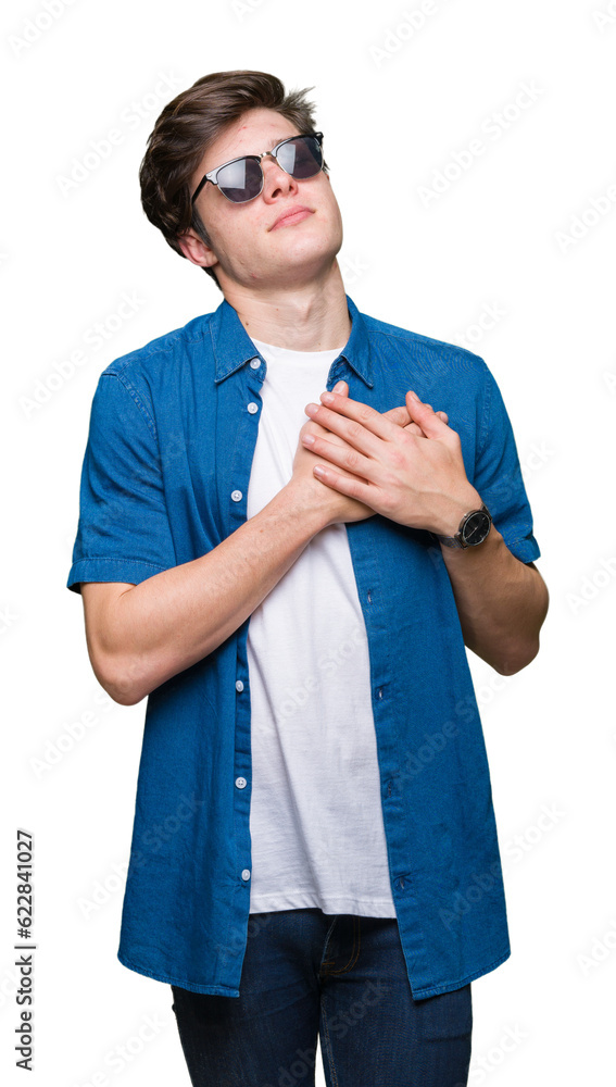 Young handsome man wearing sunglasses over isolated background smiling with hands on chest with closed eyes and grateful gesture on face. Health concept. Young handsome man wearing sunglasses over isolated background smiling with hands on chest with closed eyes and grateful gesture on face. Health concept.