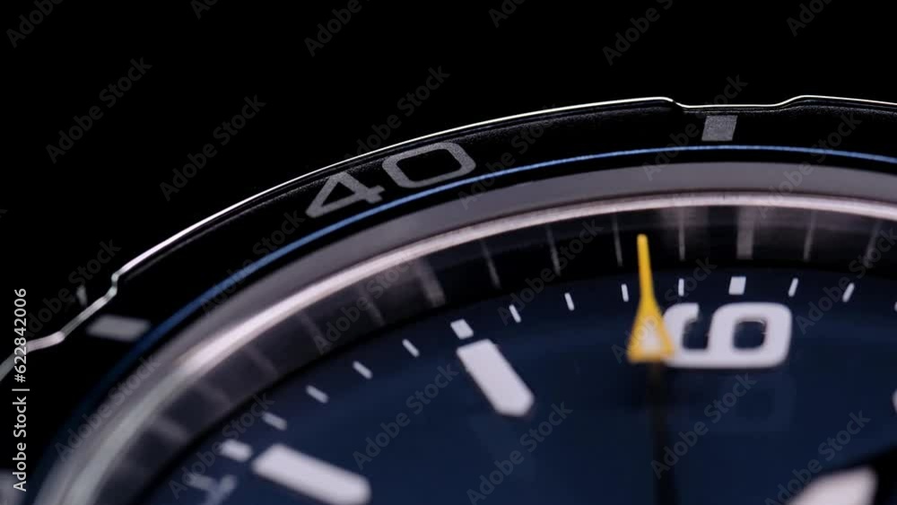 Extreme closeup of yellow second arrow passing by on blue clock face. Lengthwise view of luxury swiss watch. Closeup real time shot. Running second arrow Extreme closeup of yellow second arrow passing by on blue clock face. Lengthwise view of luxury swiss watch. Closeup real time shot. Running second arrow