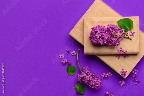 Beautiful lilac flowers and books on purple background
