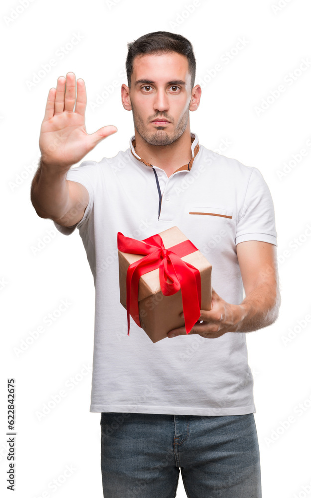 Handsome young man giving a present with open hand doing stop sign with serious and confident expression, defense gesture Handsome young man giving a present with open hand doing stop sign with serious and confident expression, defense gesture