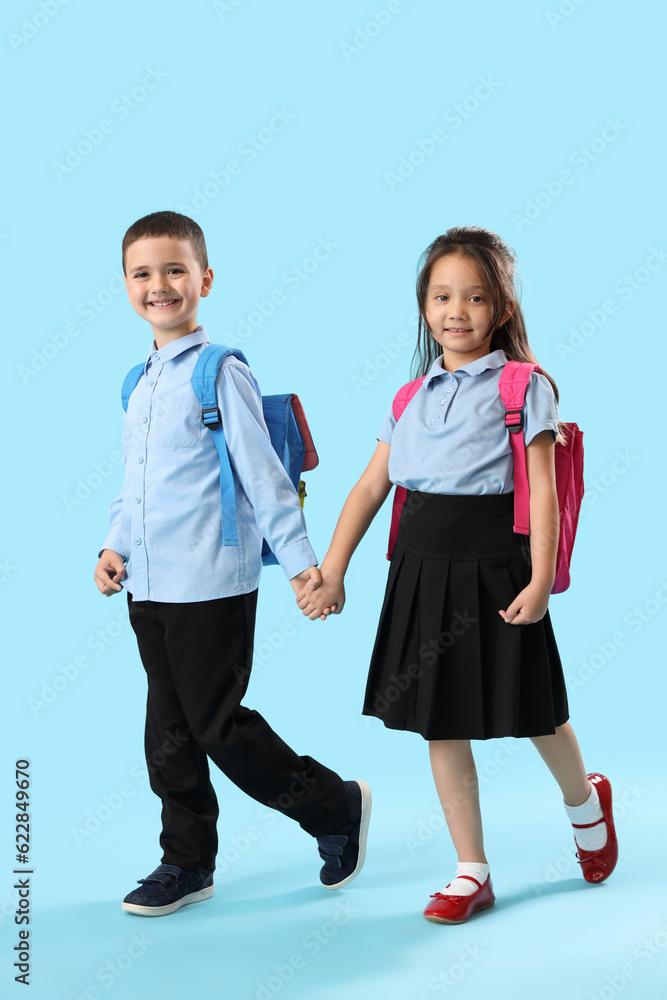Little schoolchildren holding hands on light blue background Little schoolchildren holding hands on light blue background