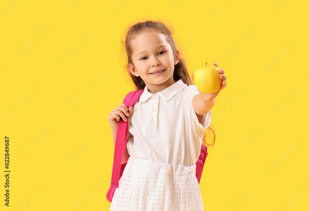 Little schoolgirl with apple on yellow background Little schoolgirl with apple on yellow background