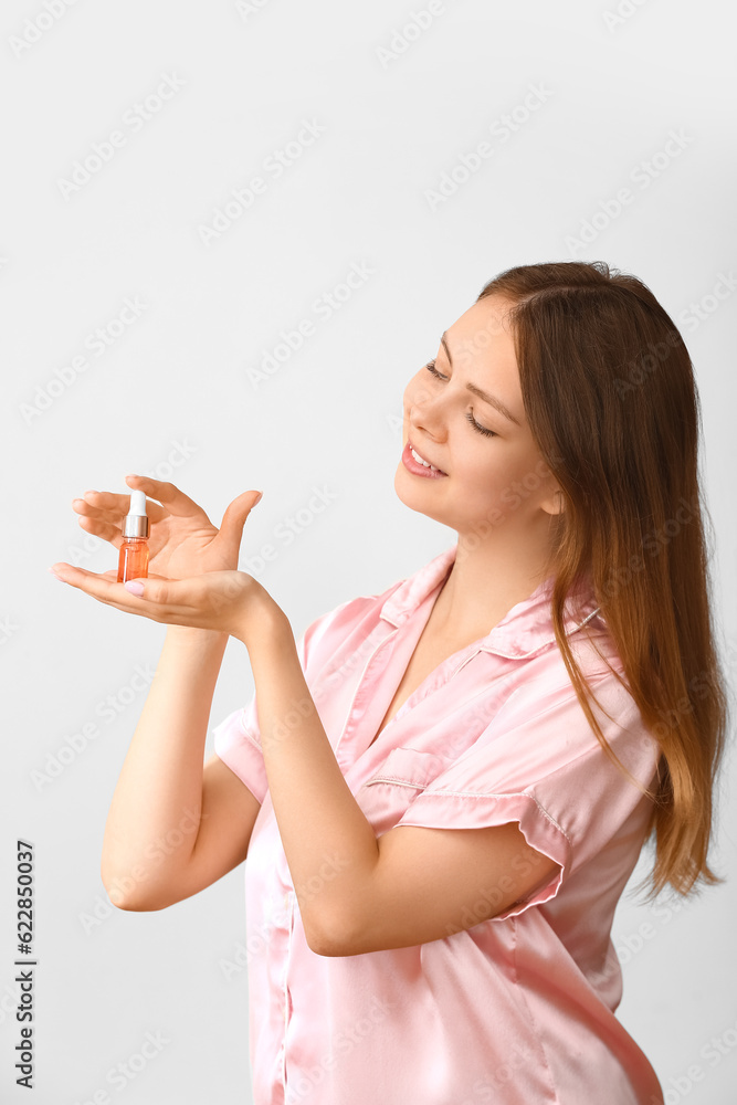 Pretty young woman with cosmetic oil on light background Pretty young woman with cosmetic oil on light background