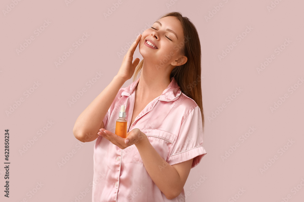 Pretty young woman with cosmetic oil on pink background Pretty young woman with cosmetic oil on pink background