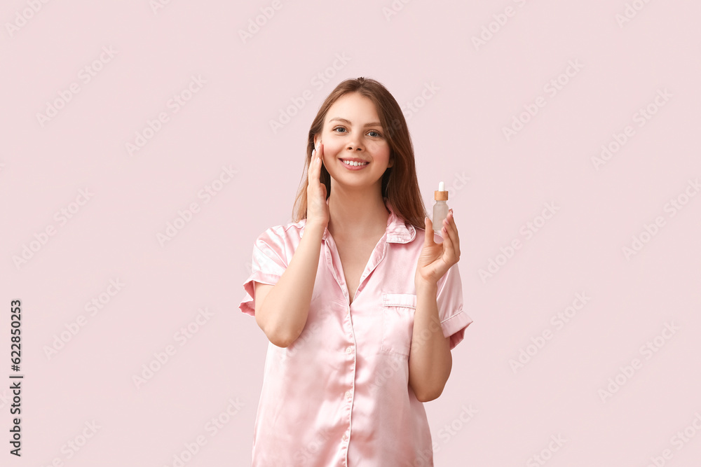Pretty young woman with cosmetic oil on light pink background Pretty young woman with cosmetic oil on light pink background