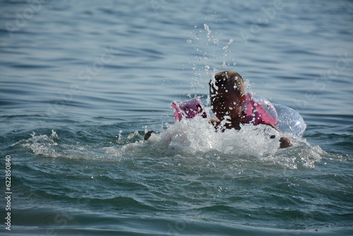 A child in a circle and armlets swims in the warm sea