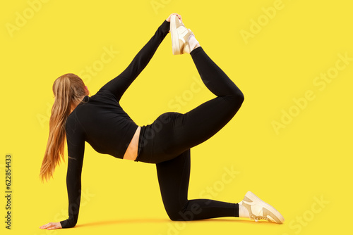 Young woman in sportswear on yellow background