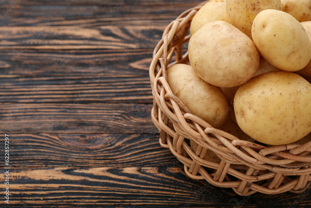 Wicker bowl with raw potatoes on wooden background Wicker bowl with raw potatoes on wooden background