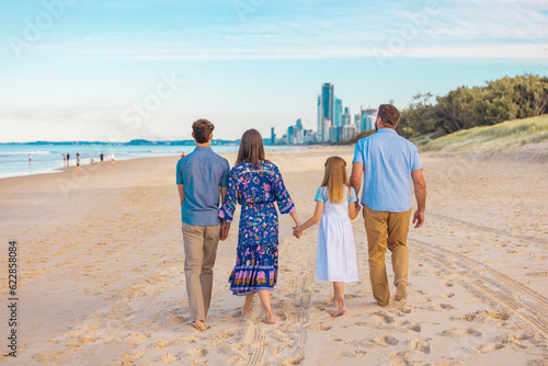 Rear view of family walking together along the beach with the Gold Coast city skyline in the background
