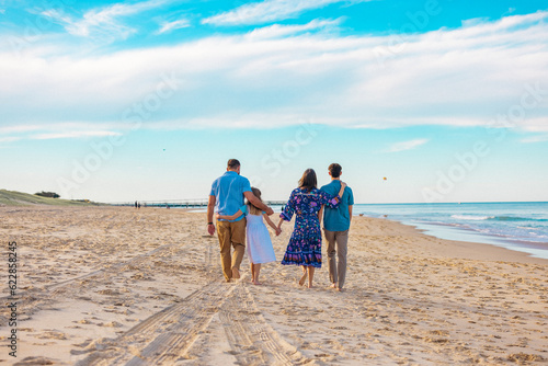 Rear view of family walking together on the beach with the Gold Coast Spit in the background