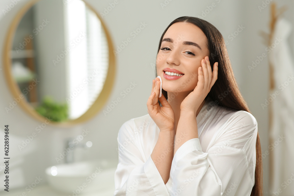 Beautiful woman removing makeup with cotton pad indoors Beautiful woman removing makeup with cotton pad indoors