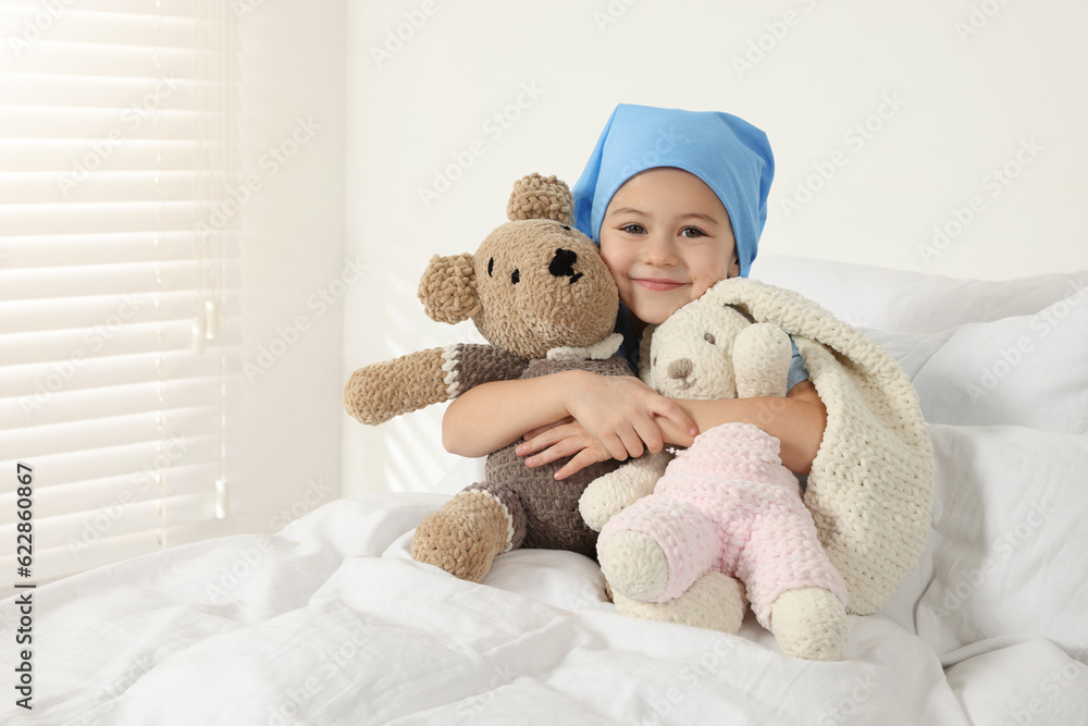 © New Africa - Childhood cancer. Girl hugging toy bunny and bear in hospital