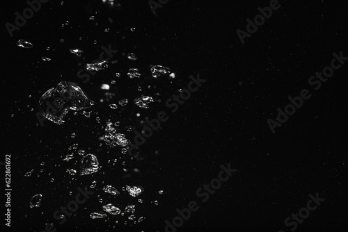 Air bubbles in water on black background, space for text