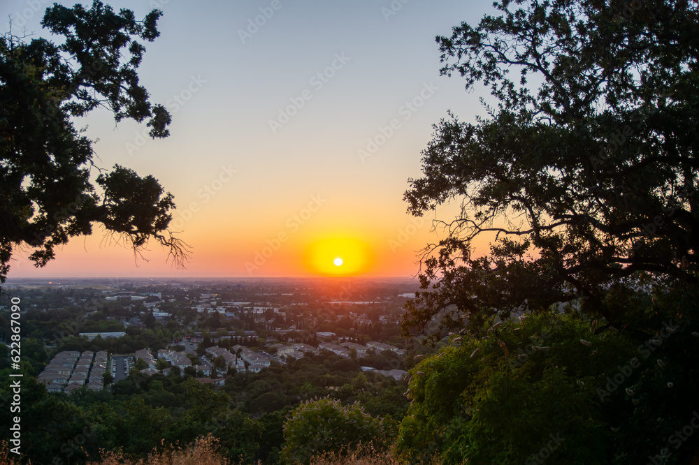 sunrise over the city with trees over the side