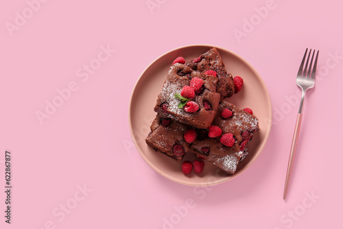Foto Plate with pieces of raspberry chocolate brownie on pink background