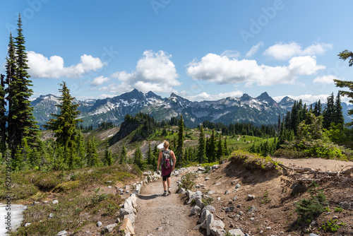 Woman hiking on trail through beautiful majestic mountains landscape in the stunning Mt. Rainier National Park, Pacific Northwest, Washington State