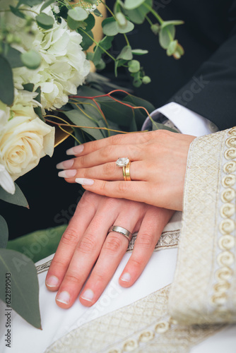 Symbol of eternal love and unity – bride and groom holding hands with rings and bouquet during wedding ceremony, romance, engagement, devotion, partnership, cultural marriage traditions, romantic mome