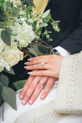 Bride and groom hands with diamond wedding rings, gold jewelry, and white floral bouquet – close-up detail of marriage ceremony, romance, engagement, eternal love, happiness, cultural wedding traditio