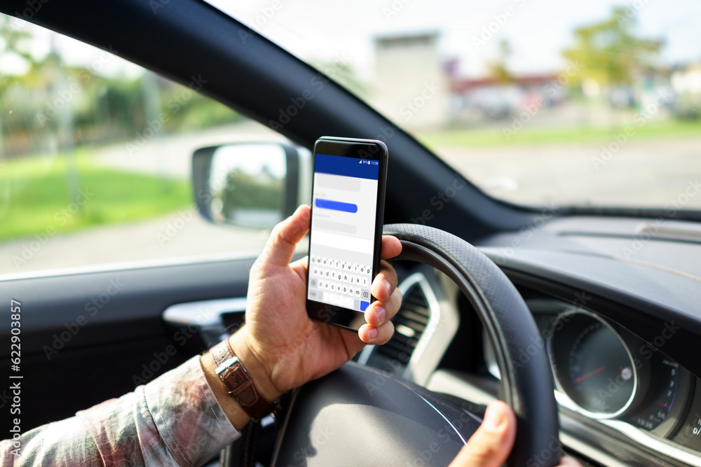 Man using a smart phone while driving a car on the road Man using a smart phone while driving a car on the road