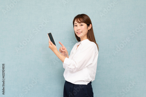 携帯電話を持つ女性　ブルーバック