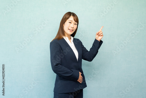 指をさす女性　ビジネス女性　スーツ（青）ブルーバック