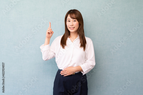 指をさす女性　ビジネス女性　ブルーバック