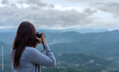 Woman photographer, taking pictures of mountain landscape with cloudy sky, travel and hobby cocept.