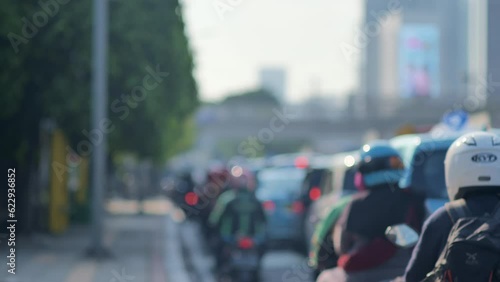 A blur image of Jakarta's urban traffic density dominated by motorcycles with a sidewalk on the side. Depicts high pollution, heat, congestion, fatigue from work, boredom, and inequality. photo