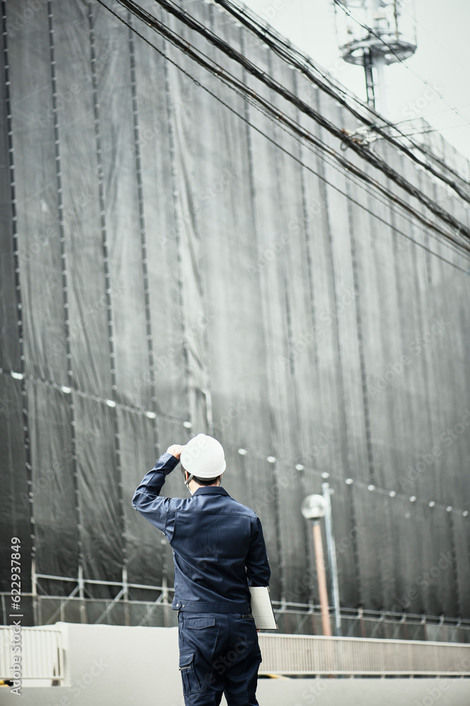 工事中の建物を見ている作業服とヘルメットの男性 工事中の建物を見ている作業服とヘルメットの男性