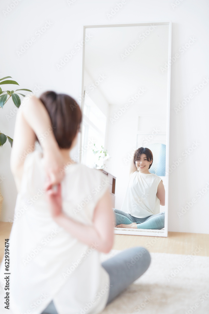 鏡に向かってストレッチをする女性 鏡に向かってストレッチをする女性