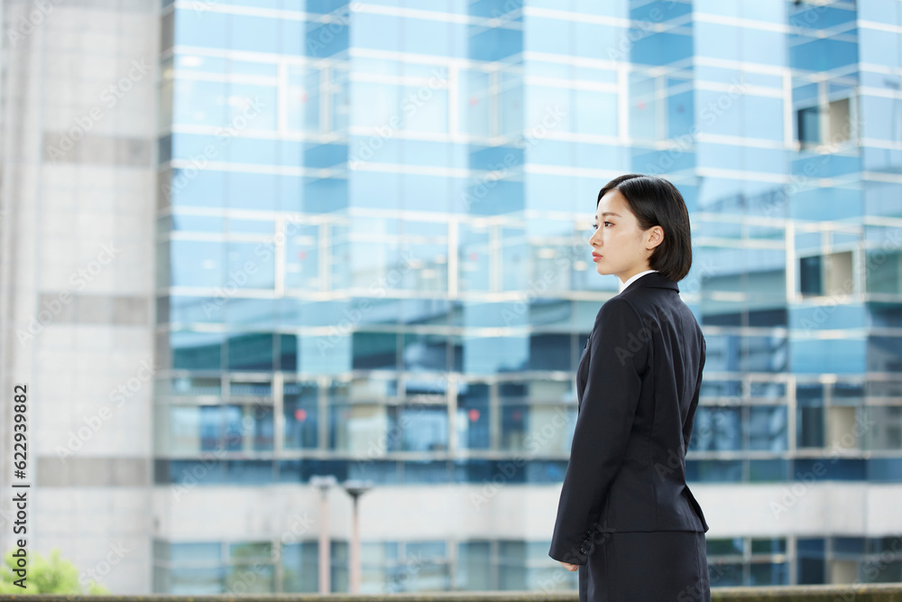 ビル の背景とリクルートスーツを着た女性