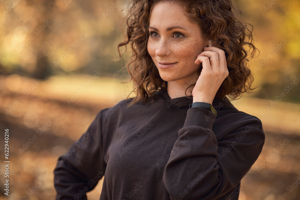 Caucasian woman applying earphones before start jogging Caucasian woman applying earphones before start jogging